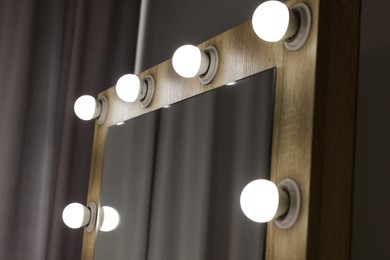 Photo of Beautiful mirror with light bulbs in makeup room, closeup