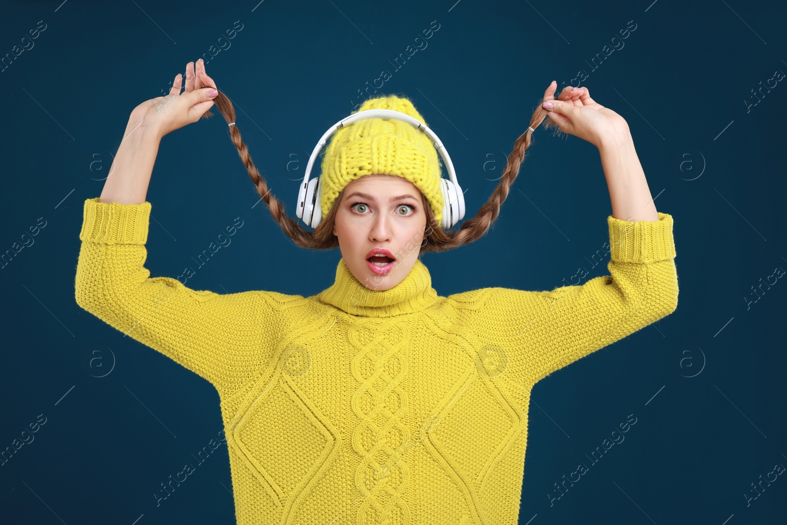 Photo of Young woman listening to music with headphones on dark blue background