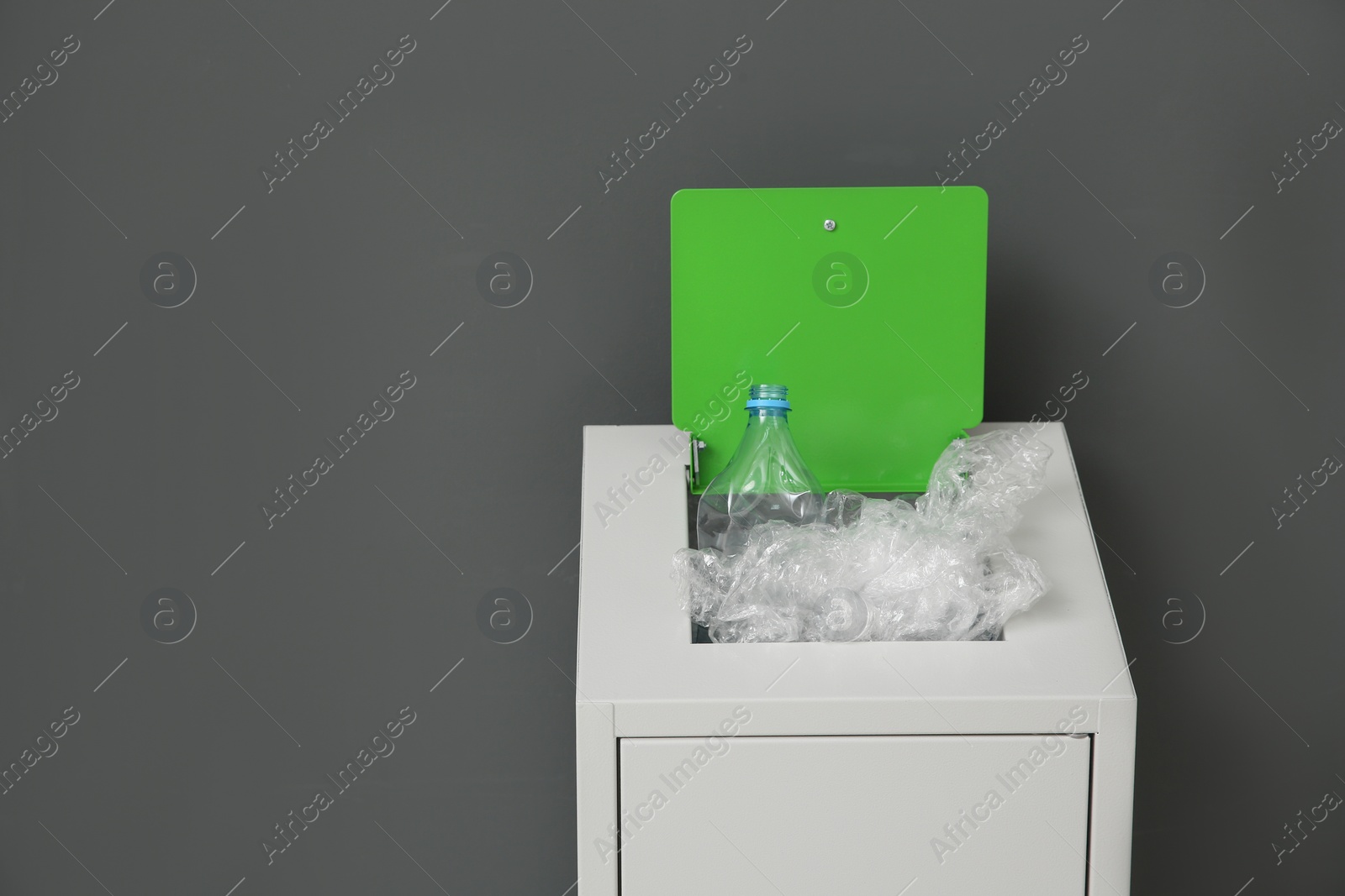 Photo of Metal bin with garbage on grey background, space for text. Waste recycling