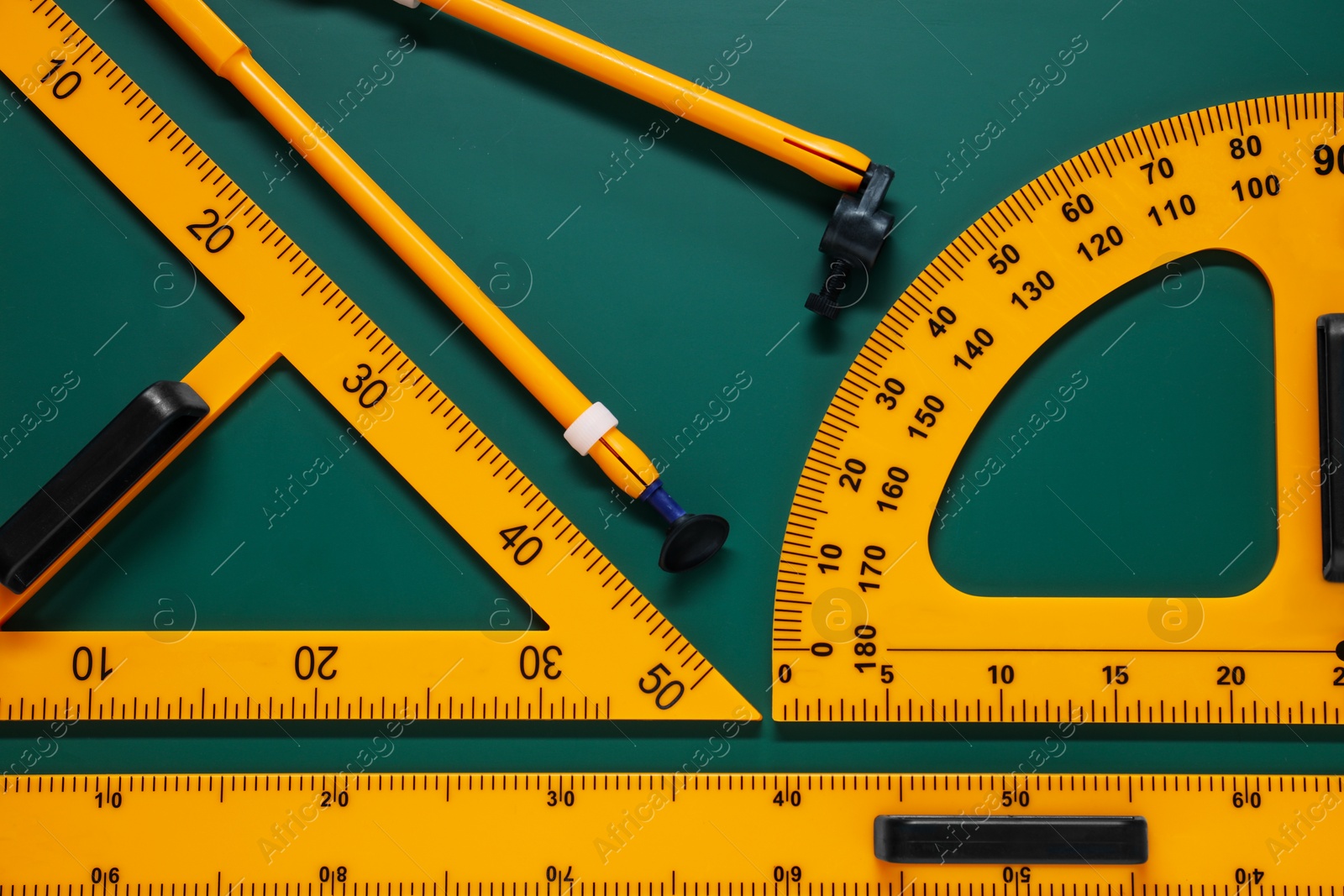 Photo of Protractor, triangle, ruler and compass on green chalkboard, flat lay