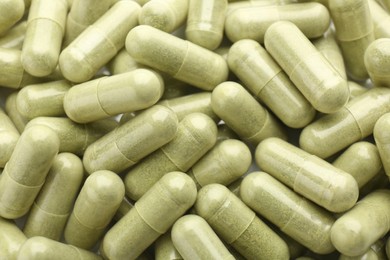 Photo of Light green vitamin capsules as background, top view