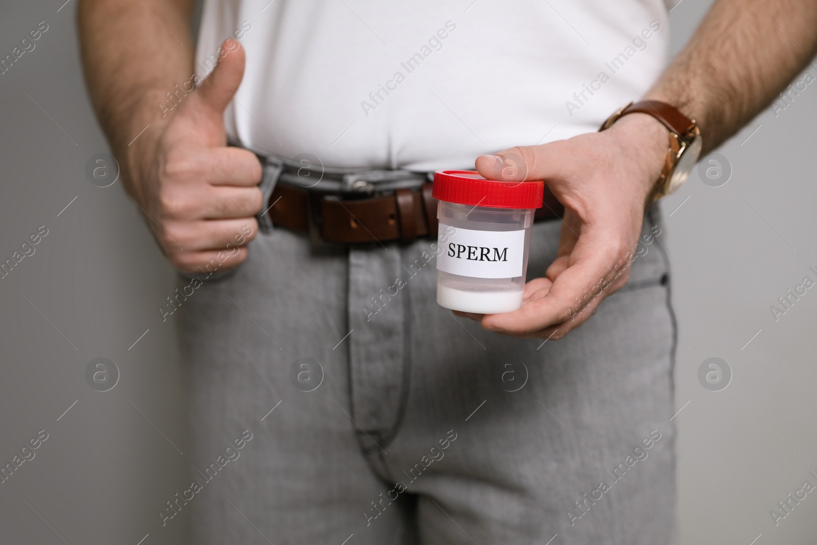 Photo of Donor holding container with sperm on beige background, closeup