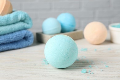 Photo of Beautiful aromatic bath bombs, sea salt and towels on light wooden table