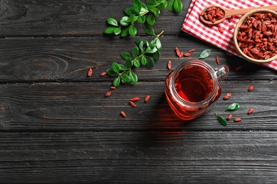 Photo of Healthy goji juice in mason jar on wooden table, flat lay. Space for text