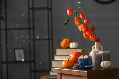 Photo of Beautiful autumn composition with cup of drink and pumpkins on wooden table indoors, space for text