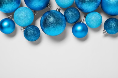 Light blue Christmas balls on white background, flat lay. Space for text