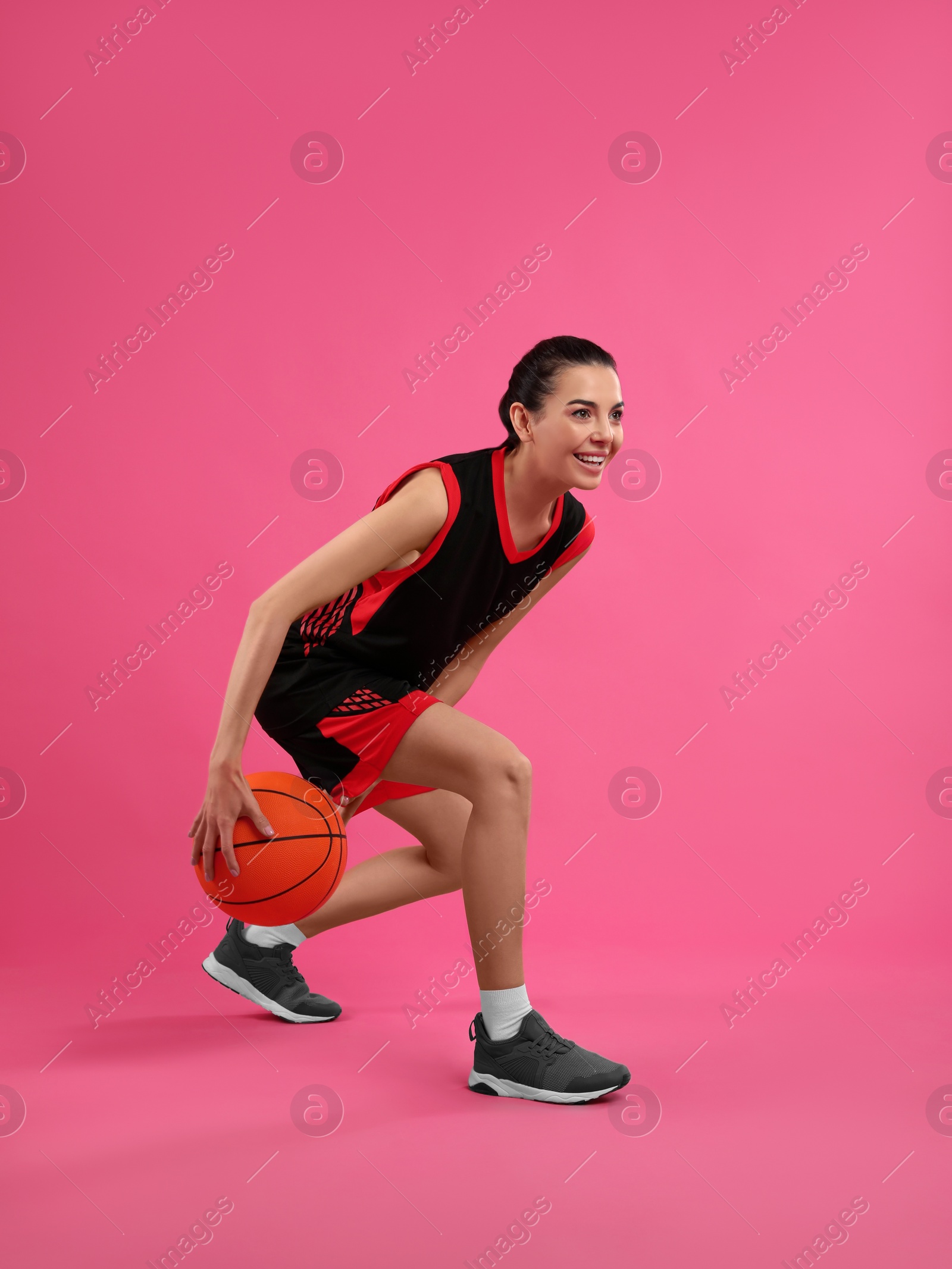 Photo of Professional sportswoman playing basketball on pink background