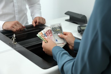 Woman with money at currency department window in bank, closeup