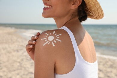 Photo of Young woman with sun protection cream on shoulder at beach, closeup