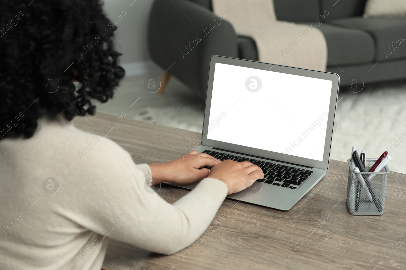 Photo of Woman using laptop at wooden desk indoors, closeup