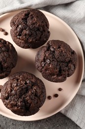 Photo of Delicious chocolate muffins on grey textured table, top view