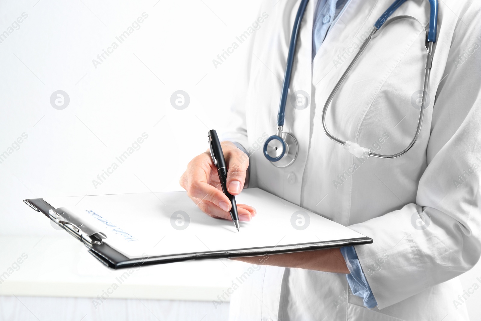 Photo of Doctor with medical insurance form on light background, closeup