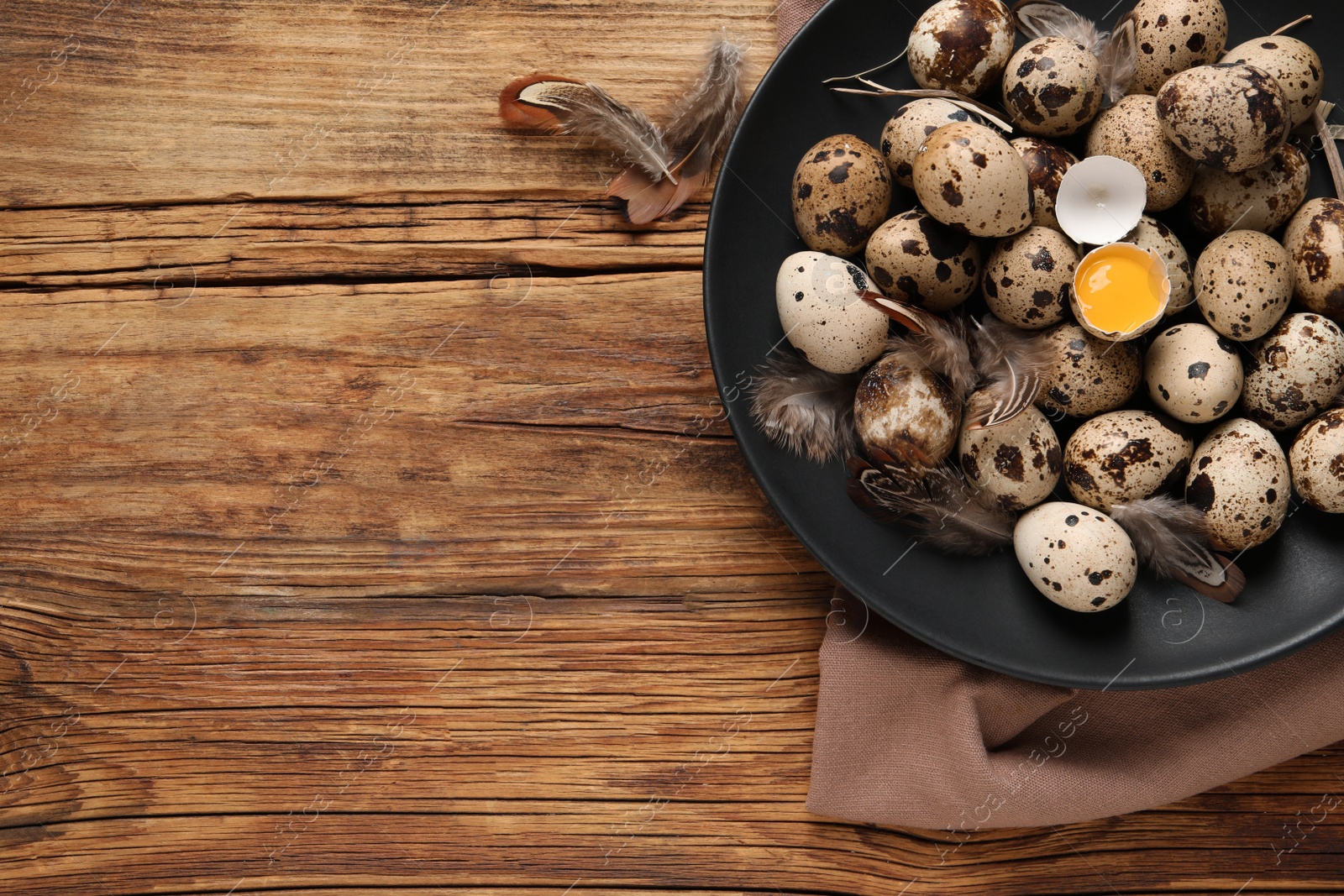 Photo of Plate with quail eggs on wooden table, top view. Space for text