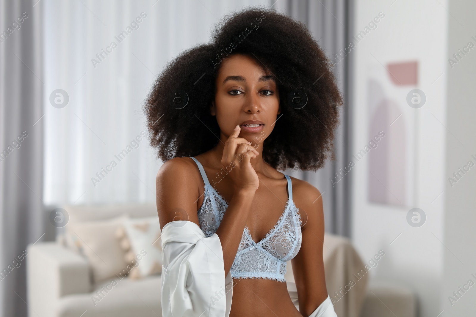 Photo of Beautiful woman in elegant light blue underwear and robe indoors