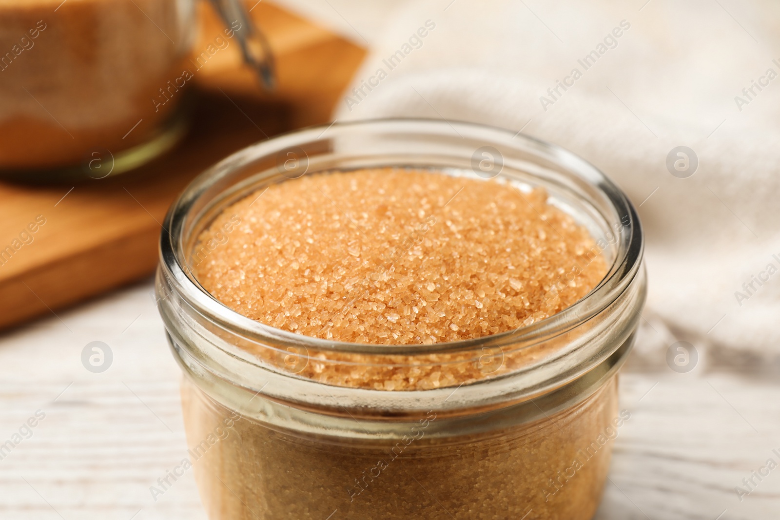 Photo of Glass jar with brown sugar on white wooden table, closeup