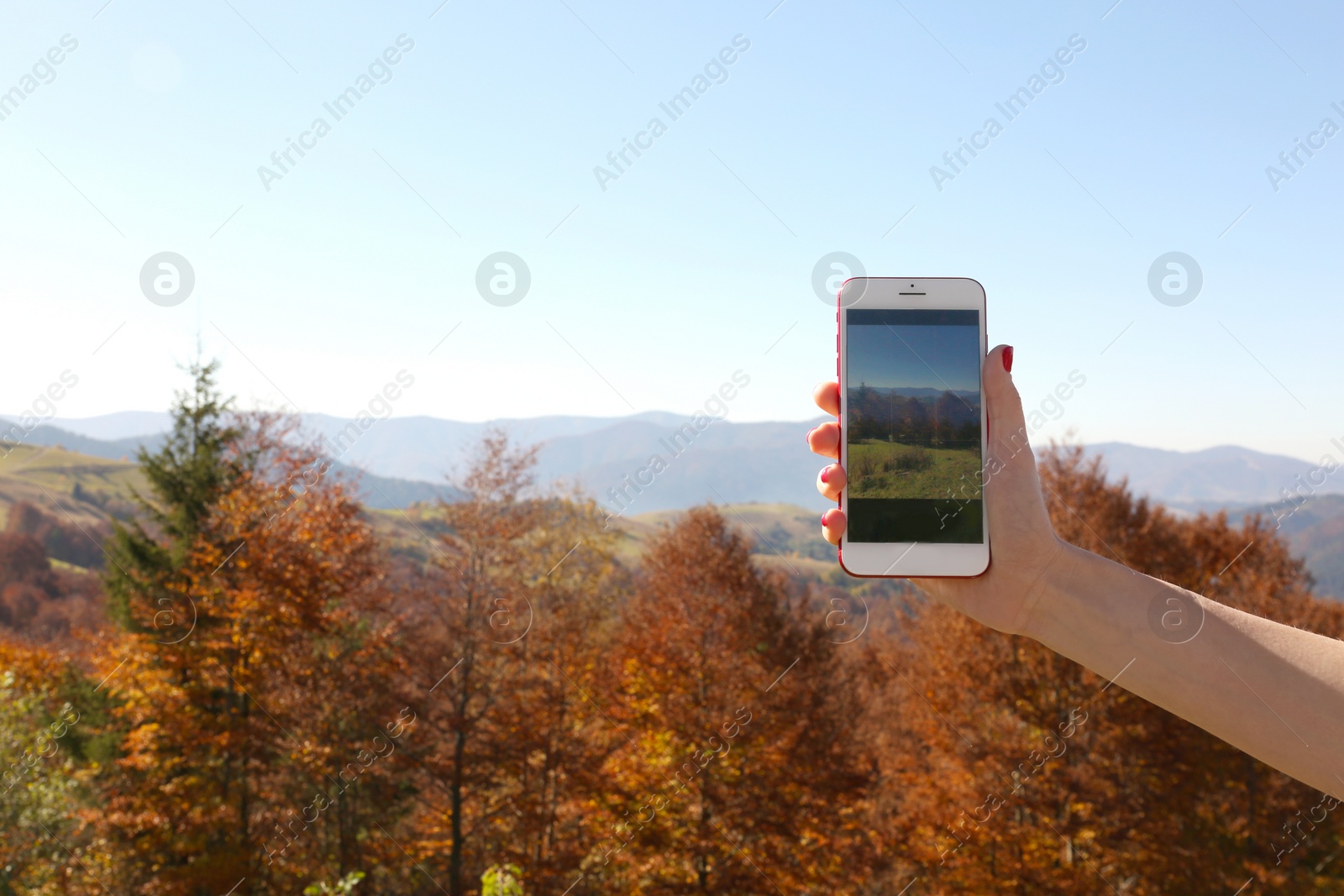 Photo of Woman taking photo of beautiful mountain landscape with smartphone