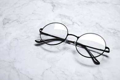 Glasses in stylish frame on white marble table, space for text