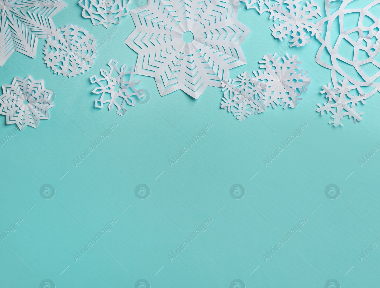 Photo of Flat lay composition with paper snowflakes on cyan background. Space for text