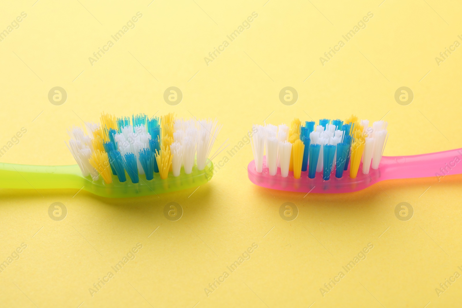 Photo of Colorful plastic toothbrushes on yellow background, closeup