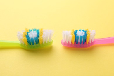 Colorful plastic toothbrushes on yellow background, closeup