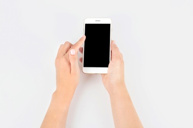 Photo of Young woman holding mobile phone with blank screen in hand on white background
