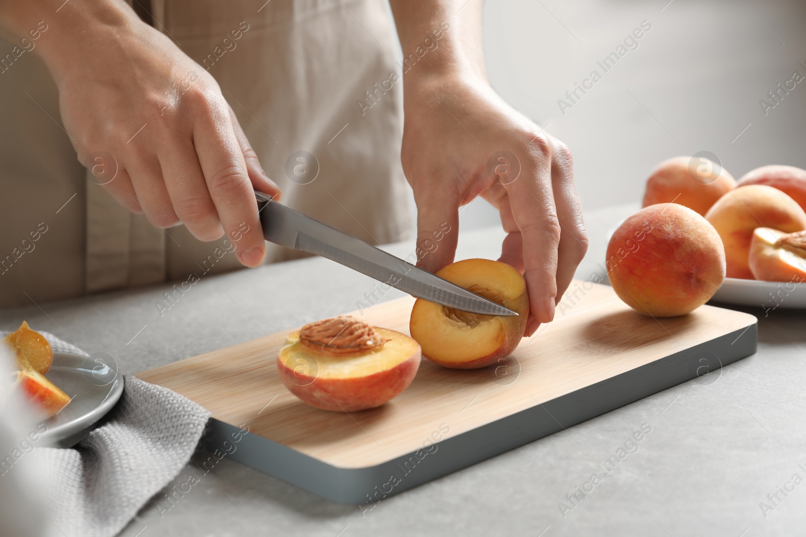 Photo of Woman cutting fresh sweet peaches on table