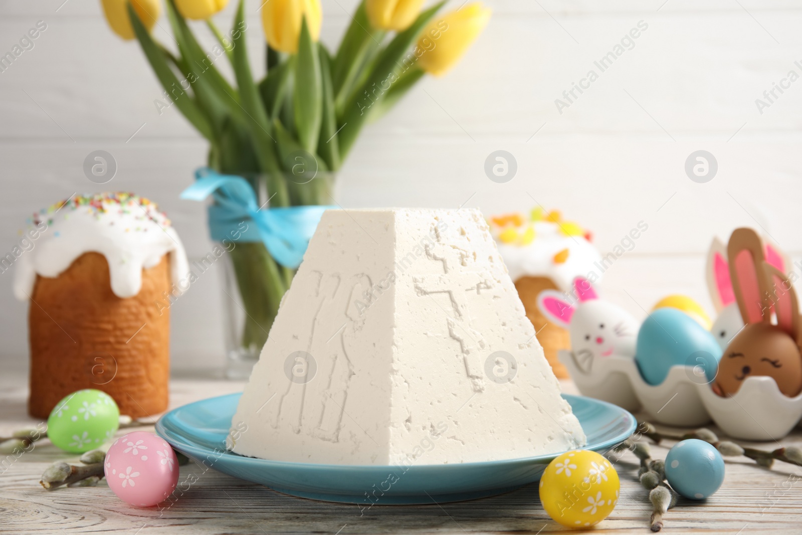Photo of Traditional cottage cheese Easter paskha and dyed eggs on white wooden table