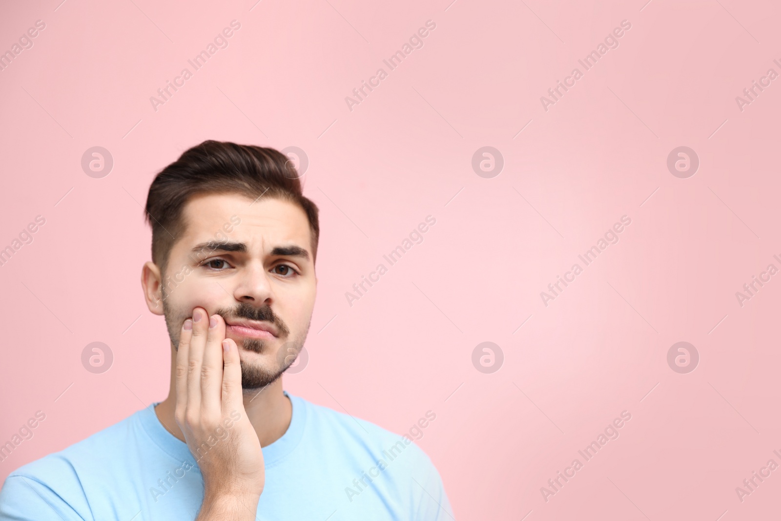 Photo of Young man suffering from strong tooth pain on color background, space for text