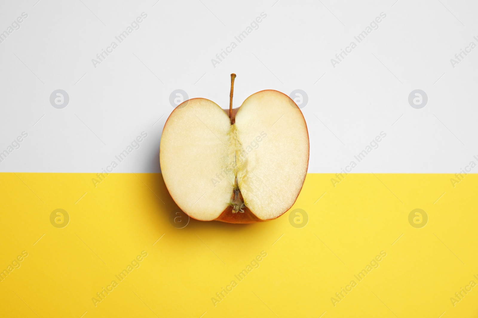 Photo of Half of ripe juicy red apple on color background, top view