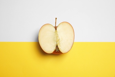 Photo of Half of ripe juicy red apple on color background, top view