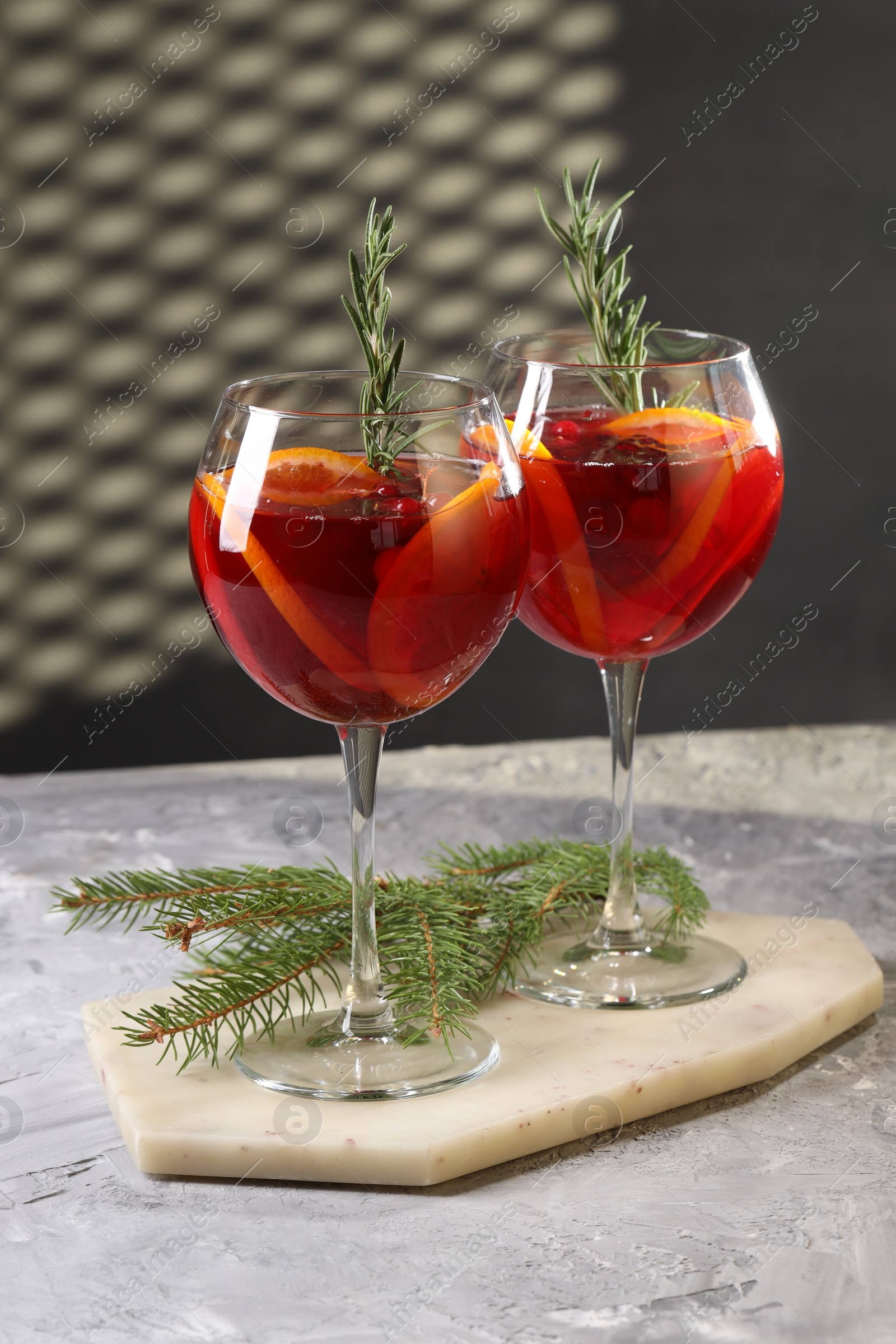 Photo of Christmas Sangria cocktail in glasses and fir tree branch on grey textured table