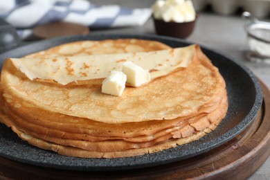 Photo of Delicious thin pancakes with butter in frying pan, closeup