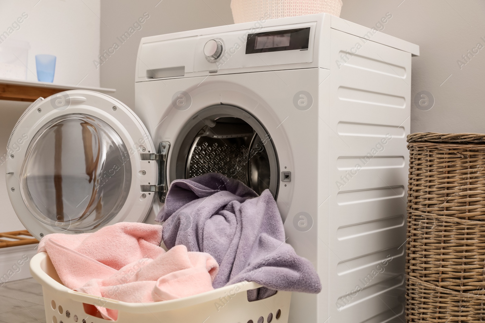 Photo of Basket with laundry and washing machine indoors