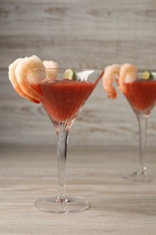 Tasty shrimp cocktail with sauce and lime in glasses on wooden table