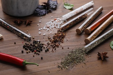 Photo of Test tubes with various spices on wooden table, closeup
