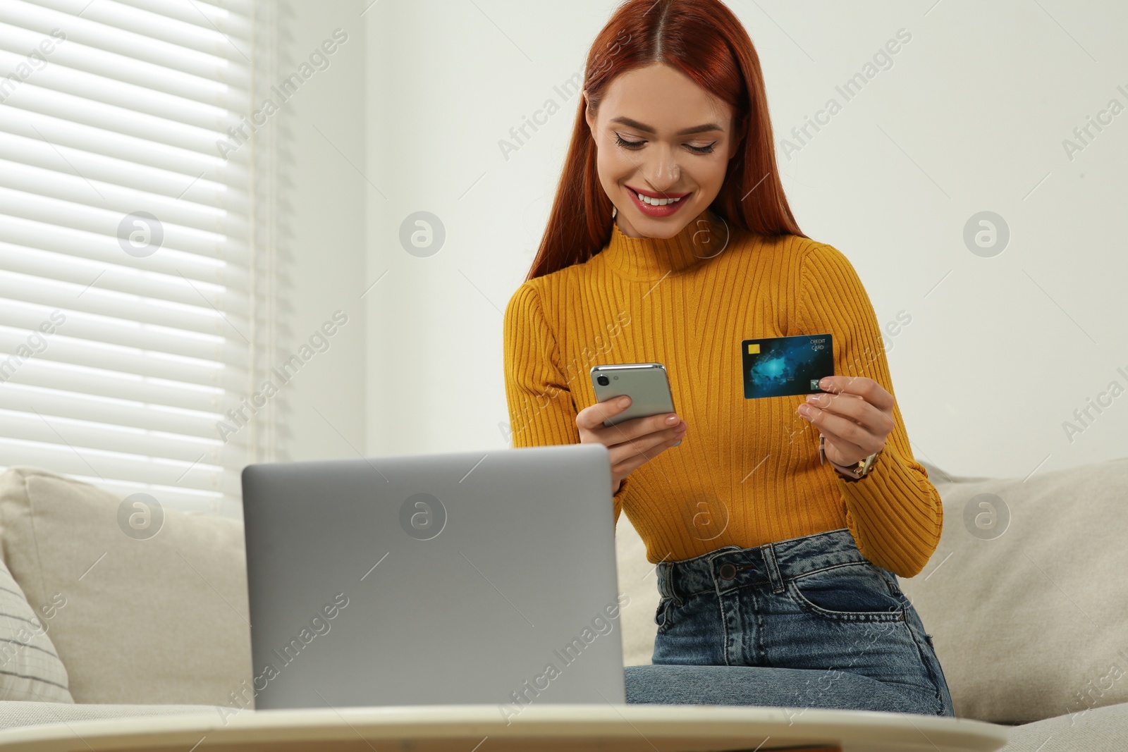 Photo of Happy woman with credit card using smartphone for online shopping at home