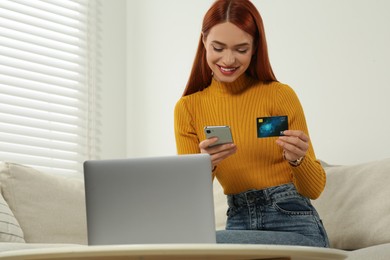 Happy woman with credit card using smartphone for online shopping at home