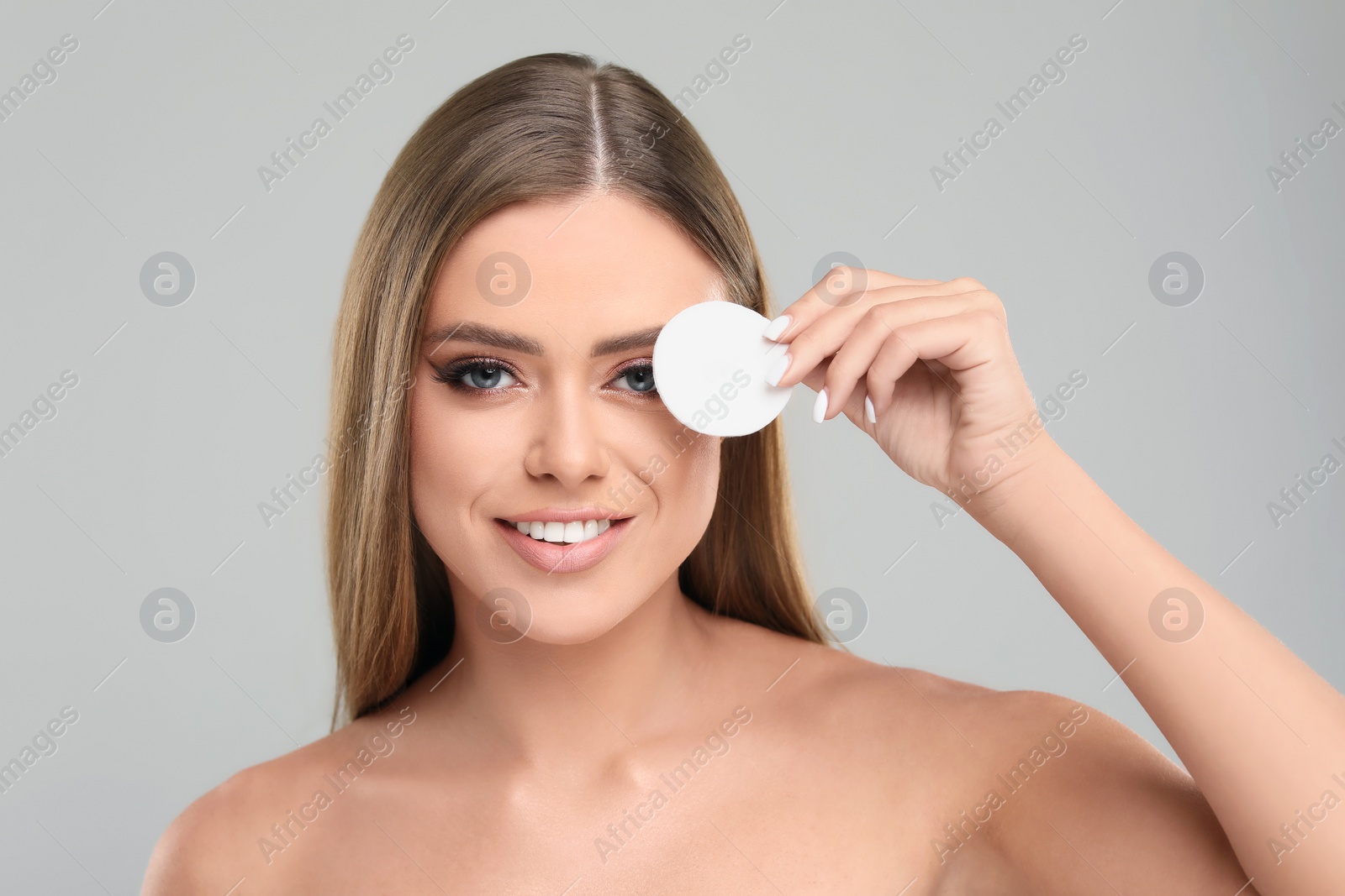 Photo of Beautiful woman with cotton pad on grey background