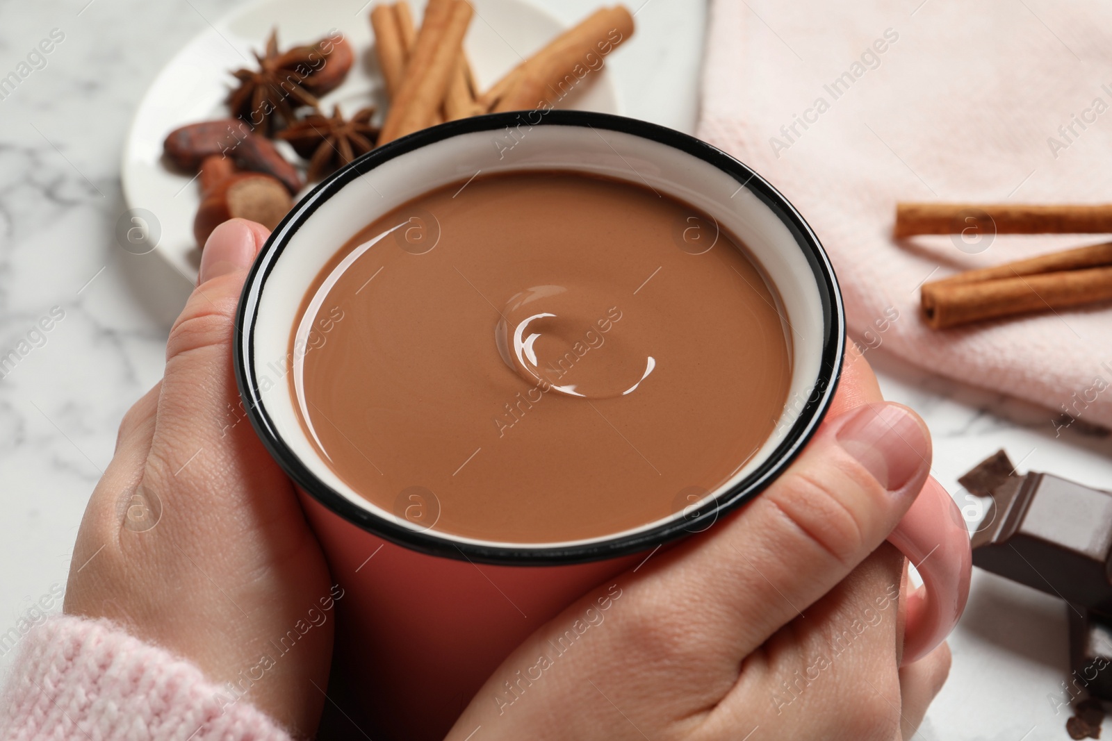 Photo of Woman with mug of yummy hot chocolate at white marble table, closeup