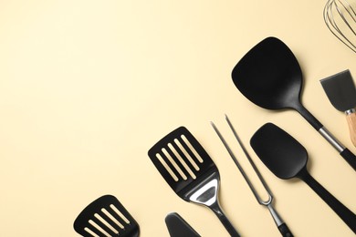 Photo of Different spatulas and carving fork on beige background, flat lay. Space for text