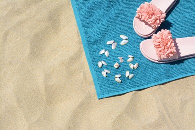 Photo of Towel, seashells and flip flops on sand, above view with space for text. Beach accessories