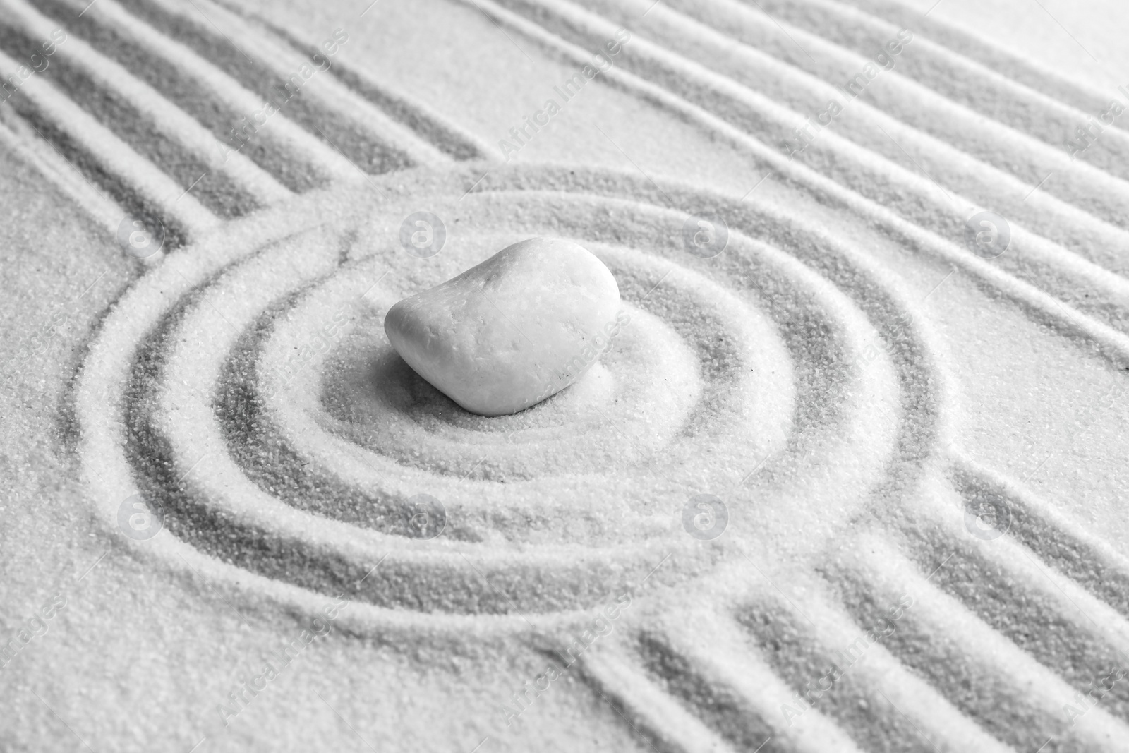 Photo of White stone on sand with pattern. Zen, meditation, harmony