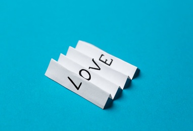 Folded paper note with word LOVE on blue background