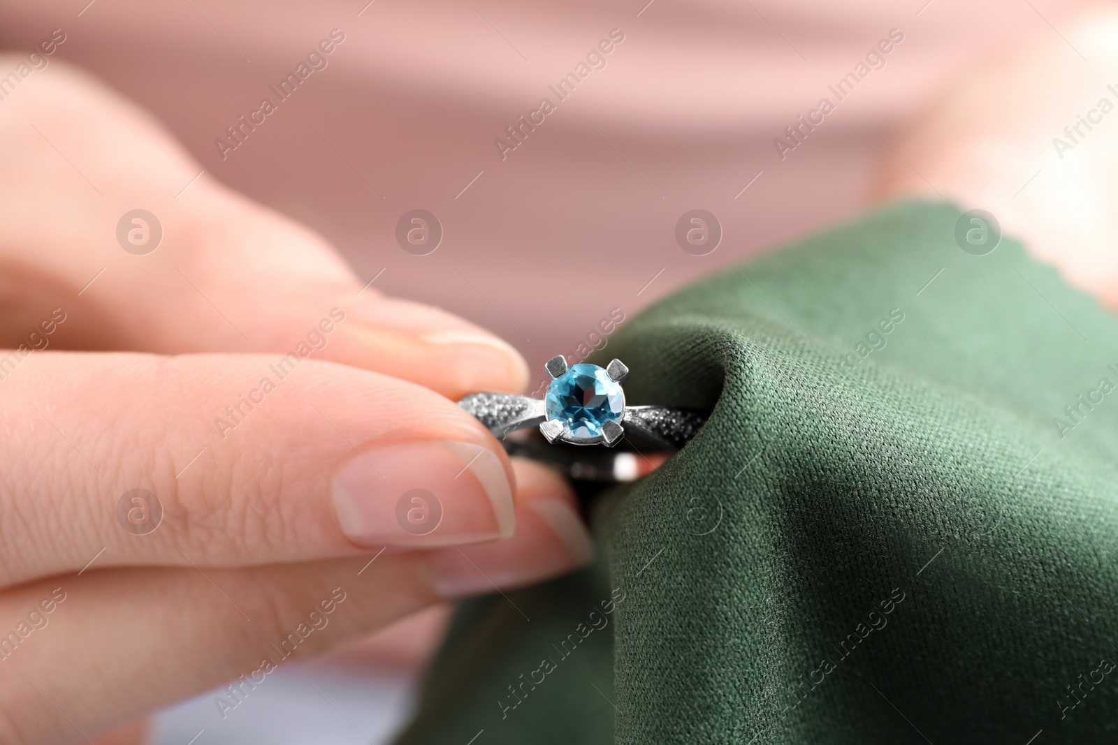 Photo of Jeweler cleaning topaz ring with microfiber cloth, closeup