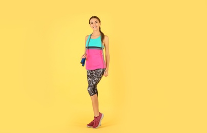 Full length portrait of young sportive woman with jump rope on color background