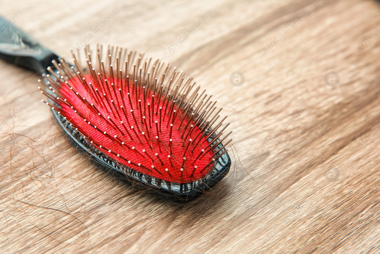 Photo of Brush with lost hair on wooden table. Alopecia problem