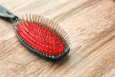 Brush with lost hair on wooden table. Alopecia problem