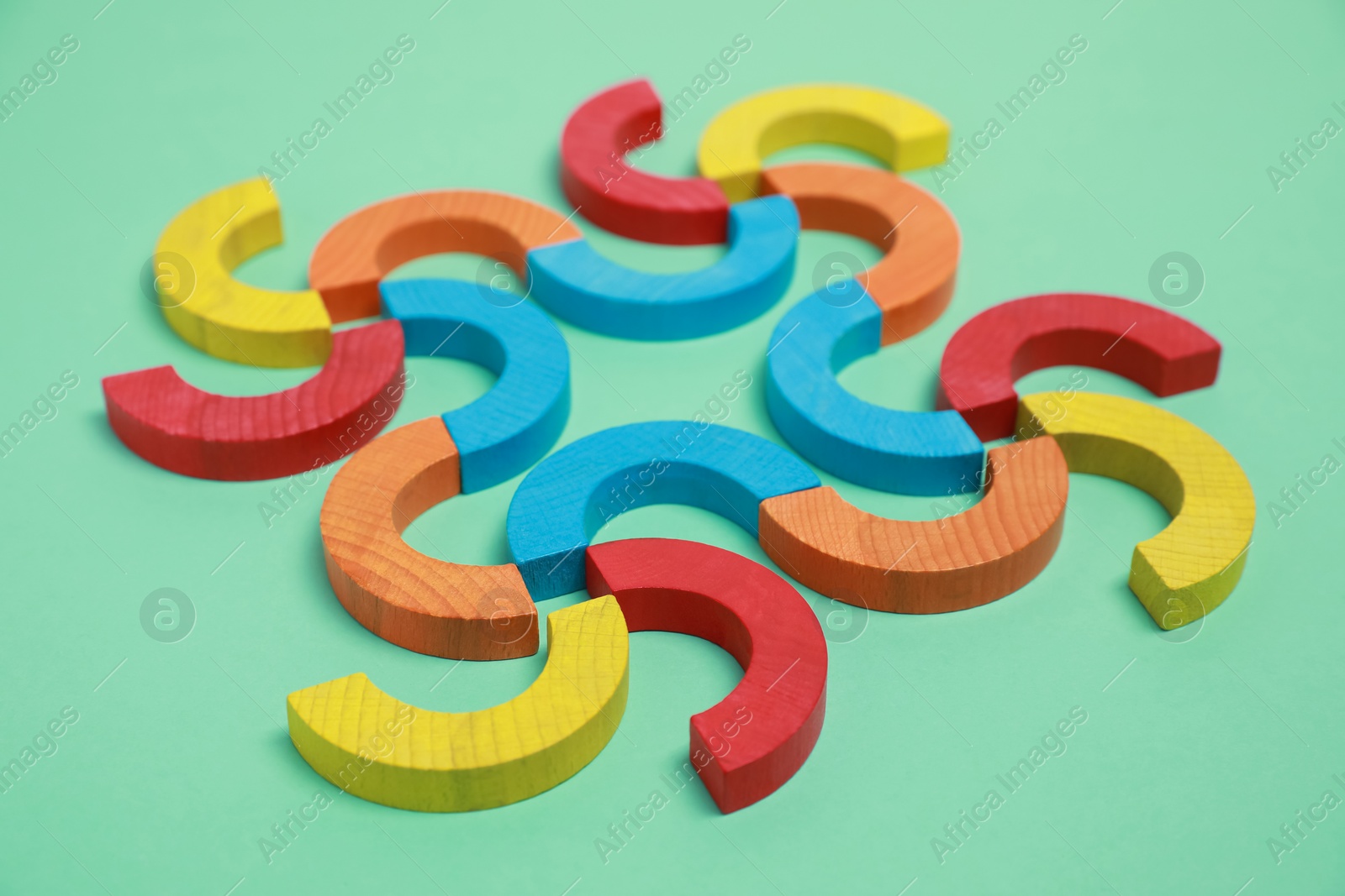 Photo of Colorful wooden pieces of play set on green background. Educational toy for motor skills development