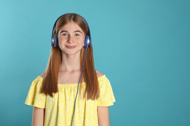 Teenage girl enjoying music in headphones on color background. Space for text