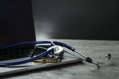 Photo of Modern electronic devices and stethoscope on grey table. Space for text